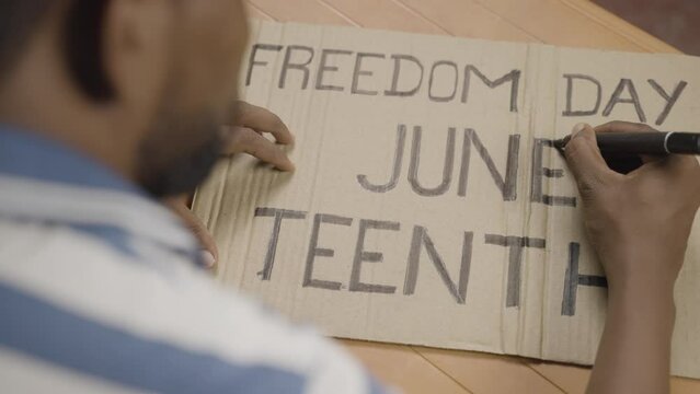 shoulder shot of activist preparing freedom day junteenth sign board for marching - concept of independence and campaign