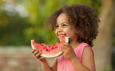 Funny Black kid eating watermelon outdoors in hot summer. Laughing baby, healthy food
