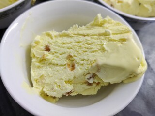 Picture of ice-cream being cut in slices with a knife for serving shot in a kitchen in indoors during summers