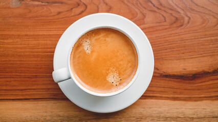 Top view of coffee cup with foam on wooden table.close-up