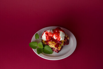 Delicious grated cake with strawberries and blueberries, with vanilla ice cream balls, poured with strawberry syrup on a red background. view from above. selective focus. for menus and ads. copy space