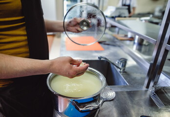 The home-made cheese maker produces handmade mozzarella with fresh quality milk. Concept: tradition, italy, mozzarella.The process of making mozzarella.