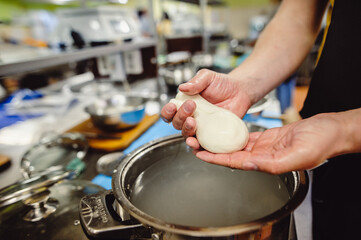 Italian hard cheese silano or caciocavallo in cheesemaker hands. The home-made cheese maker produces handmade caciocavallo. Concept: tradition, italy, mozzarella.The process of making mozzarella.