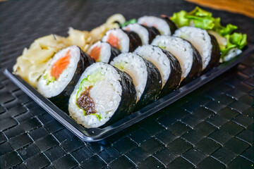 Sliced rolls of salmon and raw tuna sushi in plastic container