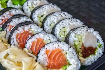 Sliced rolls of salmon and raw tuna sushi in plastic container