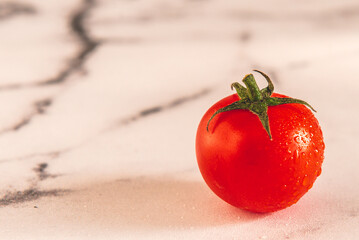 Un Tomate cherry org&aacute;nicos para ensalada, sobre una mesada de m&aacute;rmol con luz de d&iacute;a. Concepto de alimentaci&oacute;n saludable.
