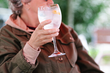 unrecognizable senior woman having a drink on a terrace