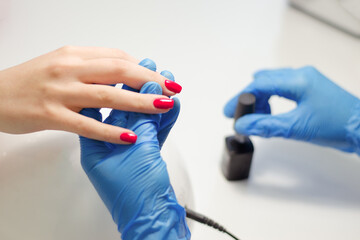 The master makes a manicure to a client in a nail salon
