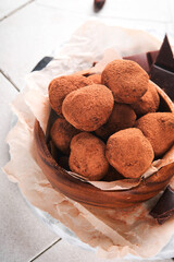 Chocolate truffles with cocoa powder in wooden dish on old cracked tile table background. Tasty sweet chocolate truffles candies. Valentine's Day and Mother's Day concept with copy space. Top view.