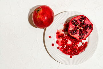 A pomegranate cut in half and whole lies on a table covered with a white tablecloth. 