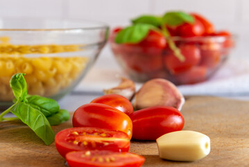 Tomates cherry orgánicos acompañados de ajo, aceite de oliva y pasta seca , sobre una mesada de mármol con luz de día. Concepto de alimentación saludable.