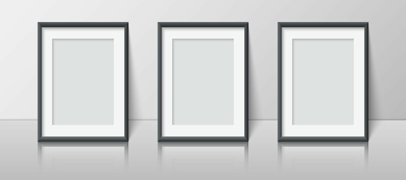 Realistic vertical blank picture frame set stands near the wall on the shelf. Three empty photo frame mockup with reflection for pictures, photograph, poster. Decorative design element interior