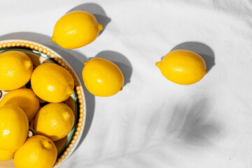 Plate with fresh lemons in a ceramic plate on the table covered with a linen tablecloth. Copy space