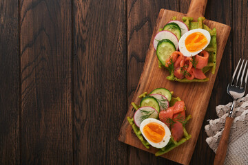 Savory waffles. Breakfast green waffles wild garlic or spinach with egg, tomato, salmon on wooden plate for breakfast on old dark wooden background. Light dinner, lunch or breakfast. Top view. Mock up