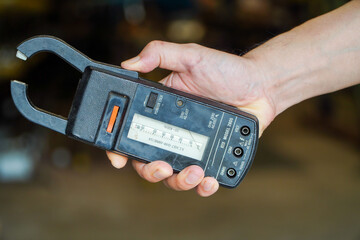 Male hand holding an analog clamp meter,concept of electric current