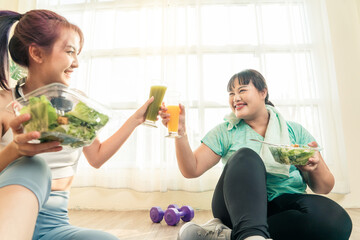 Dieting and exercise at home concept. Two Asian women body size different in sport wear sitting...