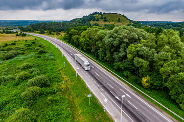 white truck driving on asphalt road on the highway. seen from the air. Aerial view landscape. drone photography. cargo delivery