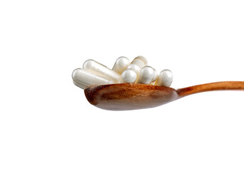 Bottom view of a wooden spoon with medical vitamin D capsules or dietary supplements.