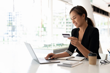 Close up of black girl hold bank credit card and type on laptop, shopping online using computer, buying goods or ordering online, entering bank accounts and details in online banking offer