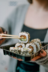 girl holding salmon sushi with chopsticks