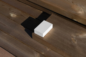 White business card, natural light photo mockup in urban outdoor environments with deep sunlit shadows. Blank isolated to place your design.