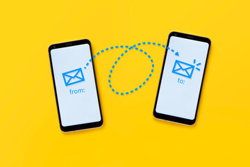 email concept. Two cell phones on a yellow background showing the operation of electronic mail through a drawing. Flat lay design.