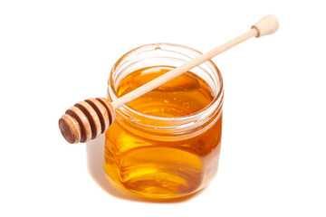 Honey dripping from honey dipper in glass jar. Healthy food concept