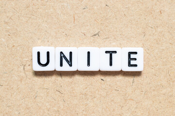 White tile alphabet letter with word unite on wood background