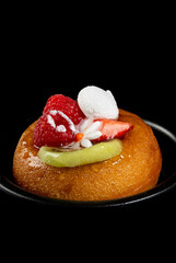 Close up studio shot of a rum baba with fresh fruit