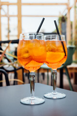 Two glasses of Aperol Spritz served on the terrace of modern bar. Popular Italian wine based...