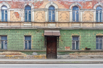 Walls of a dilapidated merchant's house with peeling paint and fallen off plaster