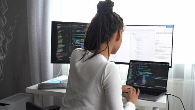 Close up shot of positive beautiful female listening to music in headphones browsing on computer