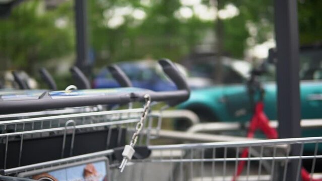 Footage of a women with a blue jeans jacket inserting a 1€ coin into a shopping cart at a grocery store in germany to buy food, drinks, fruits and other stuff