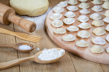 Delicious homemade dumplings with meat stacked on the kitchen board. Pelmeni