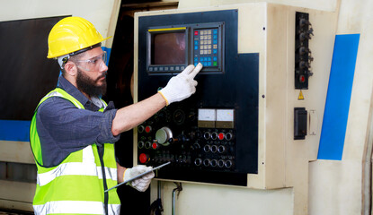 Male engineer safety helmet using a tablet to check Planning for the maintenance of metal machinery in industrial plants