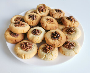 Shortbread cookies with walnuts close-up on a white plate.
