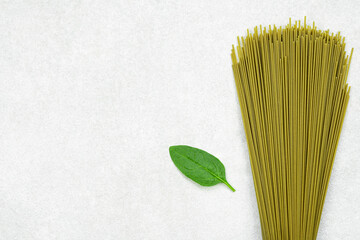 green spaghetti with spinach leaf on gray background