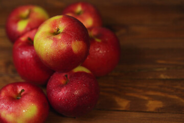 Heap of red wet apples on wooden table.