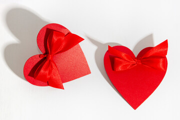 Two red hearts with a bow on a white background.