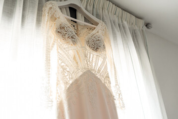 View of a bridal wedding dress hanging on the window. Wedding day concept.