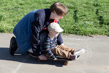 The older brother patiently and lovingly teaches the little boy his favorite hobby - to skate on a...