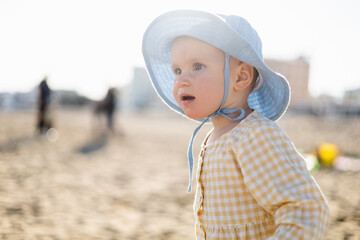 Toddler child in panama hat looking away on beach in Treviso.