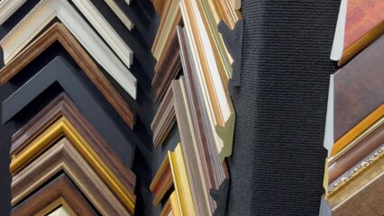 many picture and painting art wooden frame samples in different sizes and color exhibited on a black wall