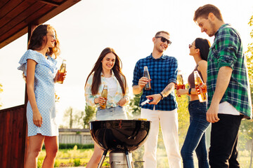 Friends have a barbecue party outdoors during outdoor recreation. Group of friends drink drinks and...