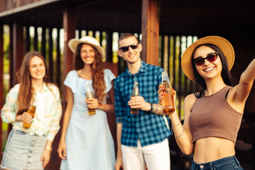 A group of cheerful young friends having a barbecue party in the backyard, taking a selfie on a mobile phone