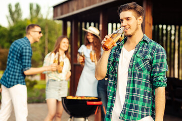 friends are having a barbecue party the backyard outdoors, a man is frying meat and drinking lemonade in the foreground