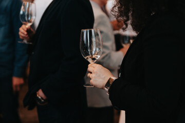 We celebrate success with a glass of white wine and champagne in hand at a special tasting with happy people.