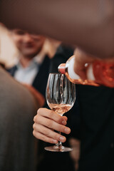We celebrate success with a glass of rose wine in hand at a special tasting with happy people.