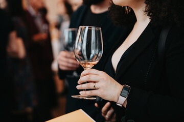 We celebrate success with a glass of rose wine in hand at a special tasting with happy people.