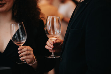We celebrate success with a glass of rose wine in hand at a special tasting with happy people.